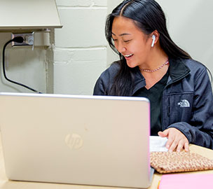 smiling woman sitting behind laptop